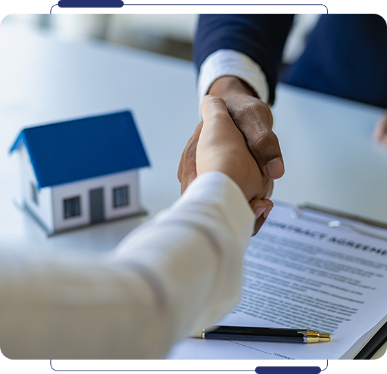 A man and woman shaking hands over a table with paperwork.
